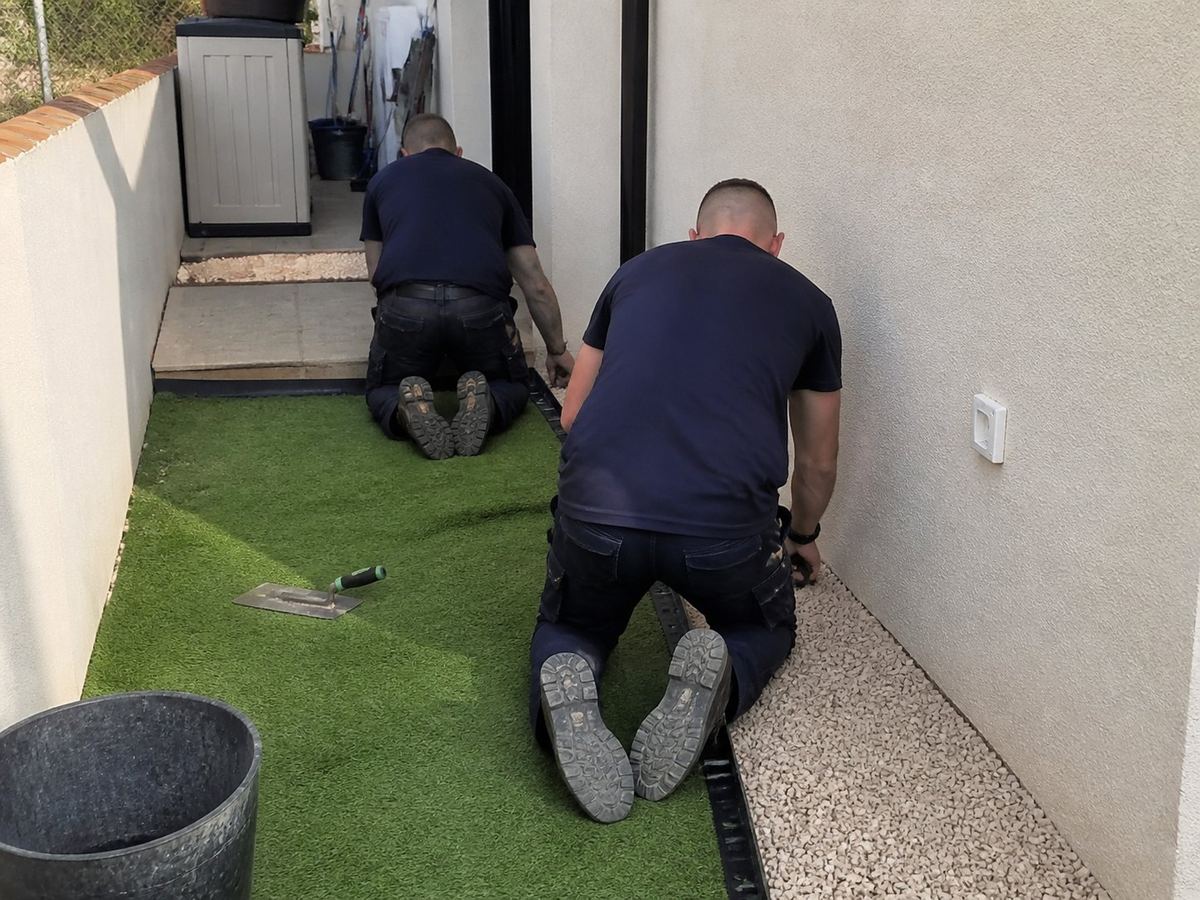 Instaladores colocando césped artificial junto a un muro